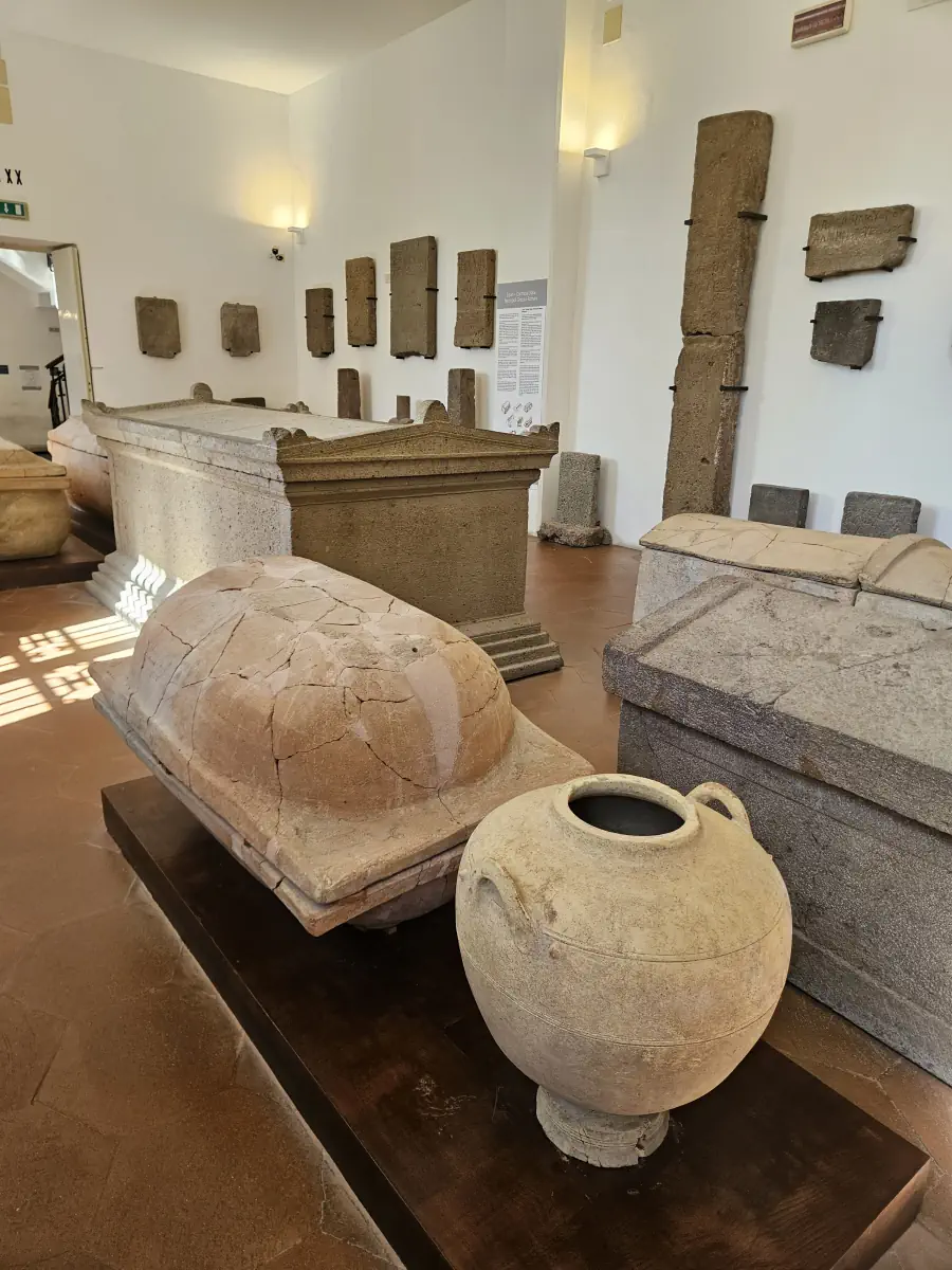 Grande jarre antique devant plusieurs sarcophages et inscriptions au musée archéologique de Lipari.
